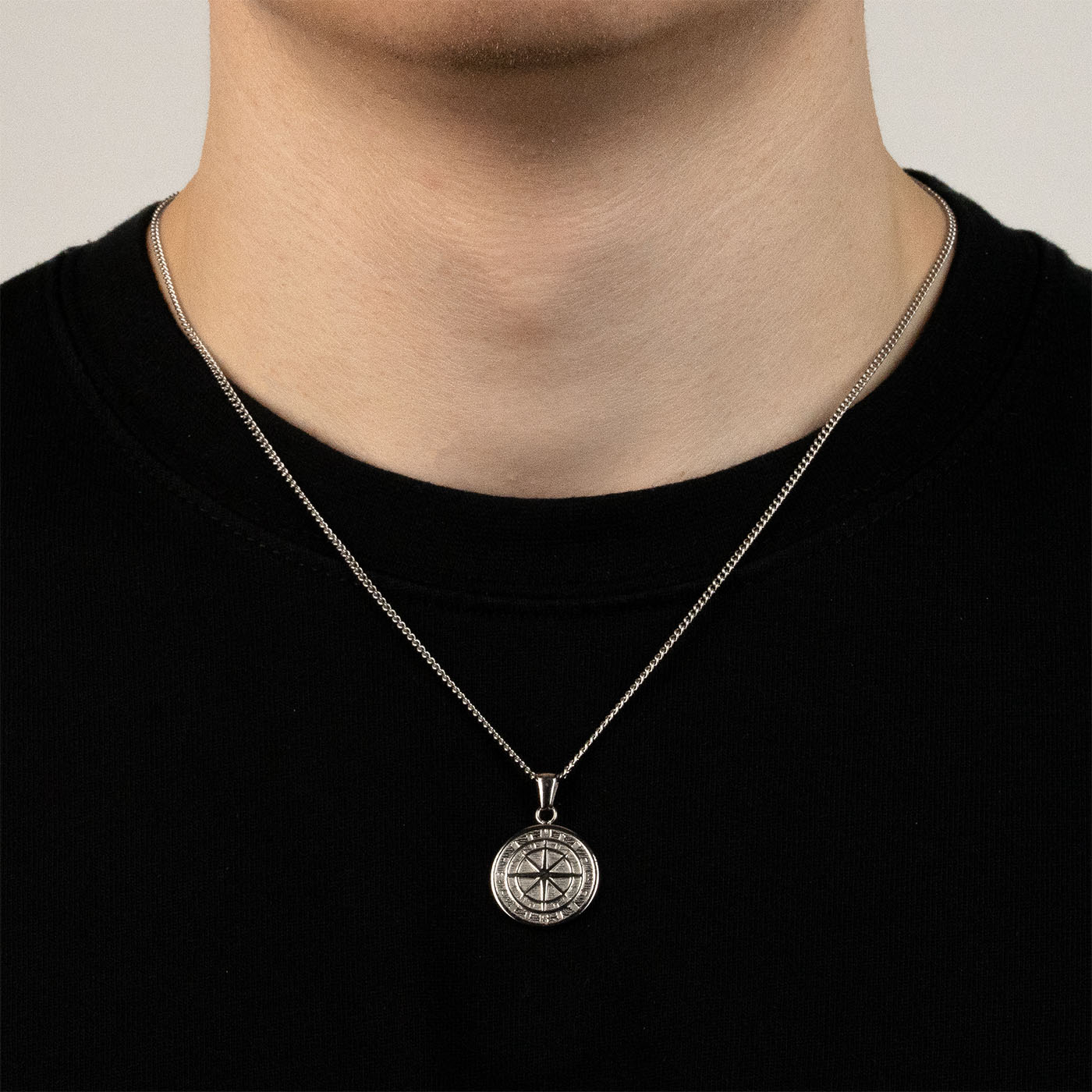 Model trägt eine silberfarbenen Kompass-Anhänger aus 316L Edelstahl mit einem Gewicht von 4,0 g.