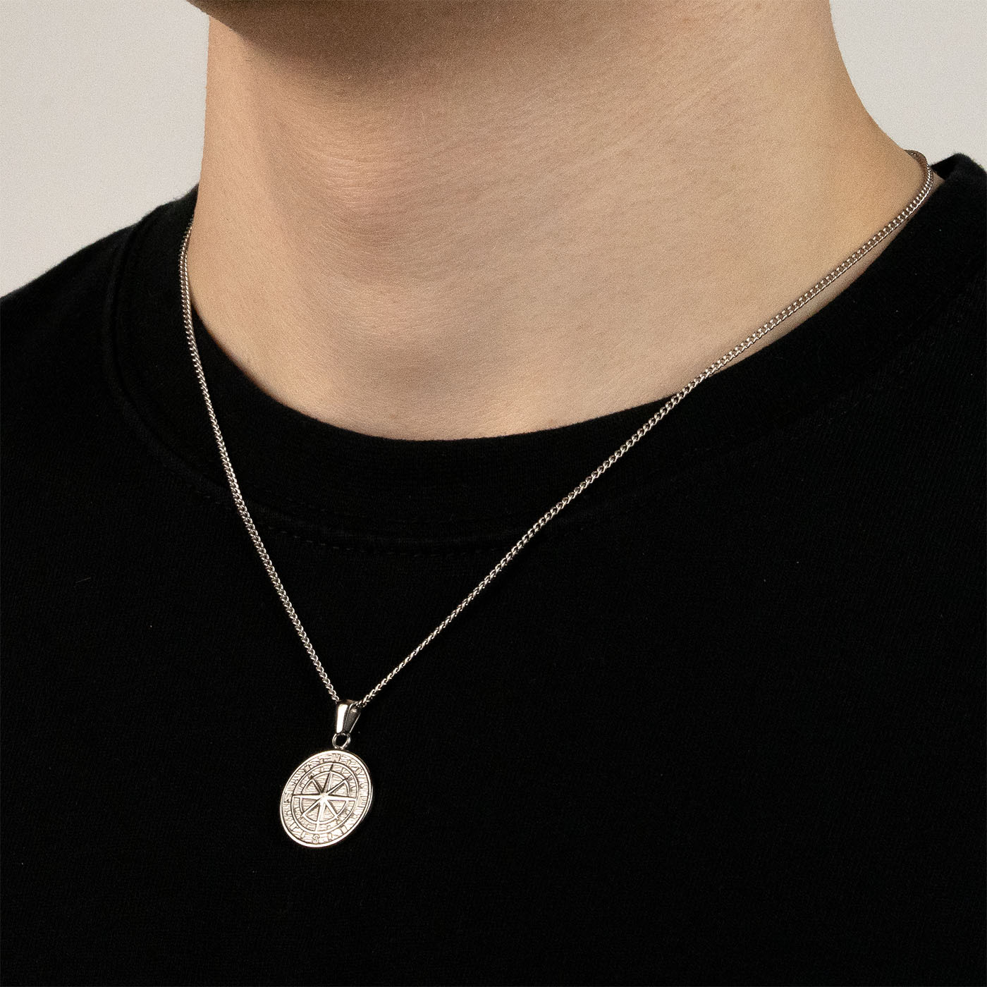 Model trägt eine silberfarbenen Kompass-Anhänger aus 316L Edelstahl mit einem Gewicht von 4,0 g.