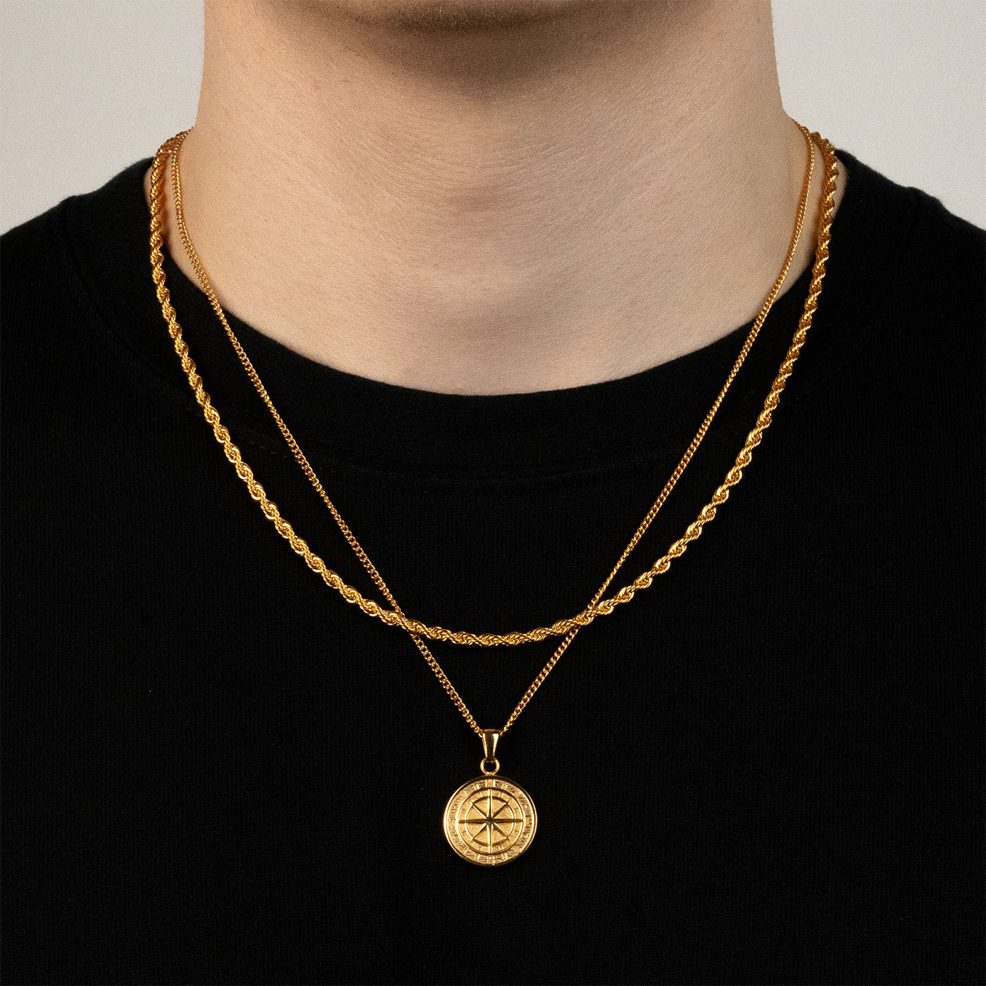 Model trägt ein goldfarbenes Schmuckset aus einer Rope-Halskette und einem Kompass-Anhänger aus 316L Edelstahl mit einem Gesamtgewicht von 15,4 g.