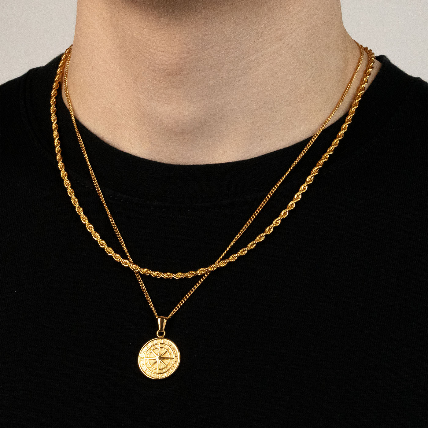 Model trägt ein goldfarbenes Schmuckset aus einer Rope-Halskette und einem Kompass-Anhänger aus 316L Edelstahl mit einem Gesamtgewicht von 15,4 g.