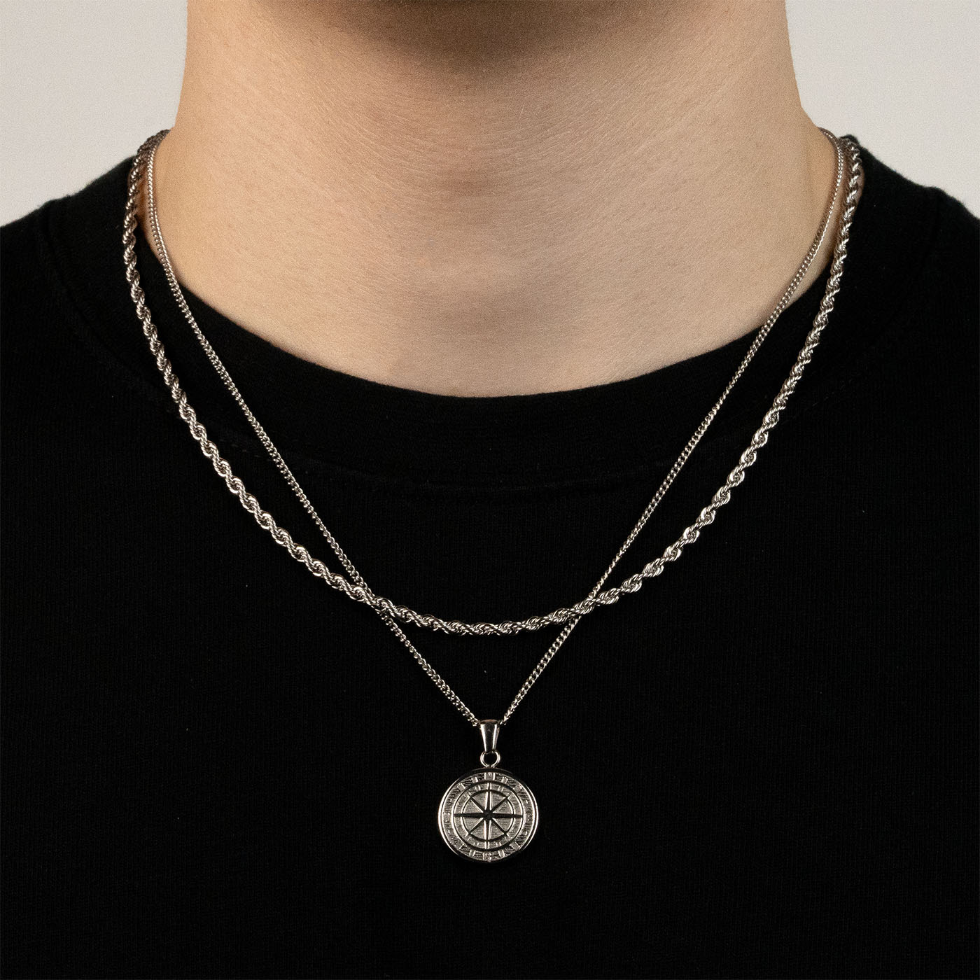 Model trägt ein silberfarbenes Schmuckset aus einer Rope-Halskette und einem Kompass-Anhänger aus 316L Edelstahl mit einem Gesamtgewicht von 15,4 g.