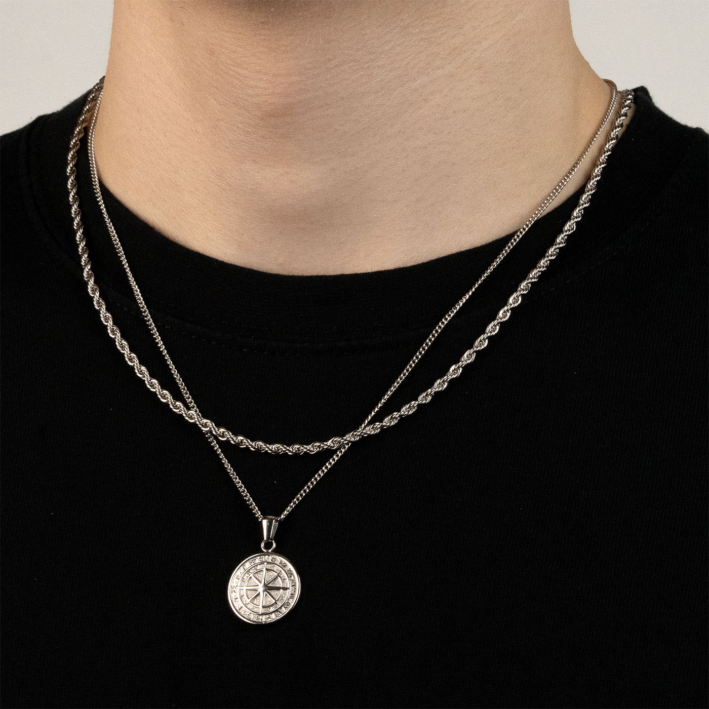 Model trägt ein silberfarbenes Schmuckset aus einer Rope-Halskette und einem Kompass-Anhänger aus 316L Edelstahl mit einem Gesamtgewicht von 15,4 g.