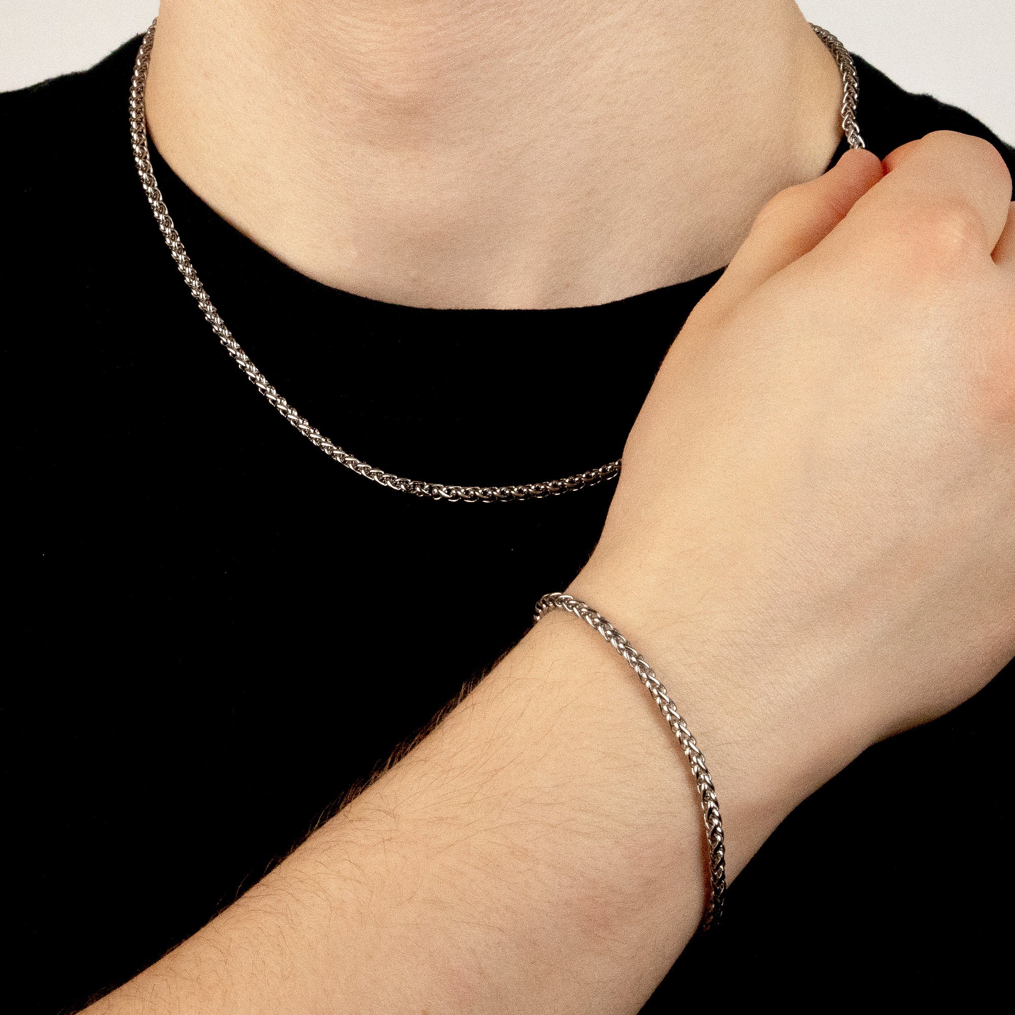 Model trägt ein silberfarbenes Schmuckset aus einer Wheat-Halskette und einem passenden Wheat-Armband aus 316L Edelstahl mit einem Gesamtgewicht von 18,6 g.